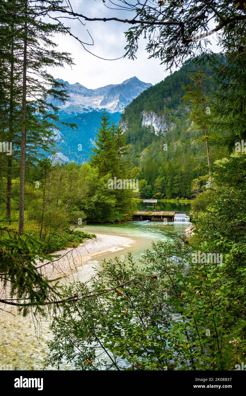 Famoso lago verde Schiederweiher vicino al villaggio di Hinterstoder. Piccolo stramazzo e diga sul lago con acqua corrente. Grandi montagne austriache sullo sfondo. Morbido Foto Stock