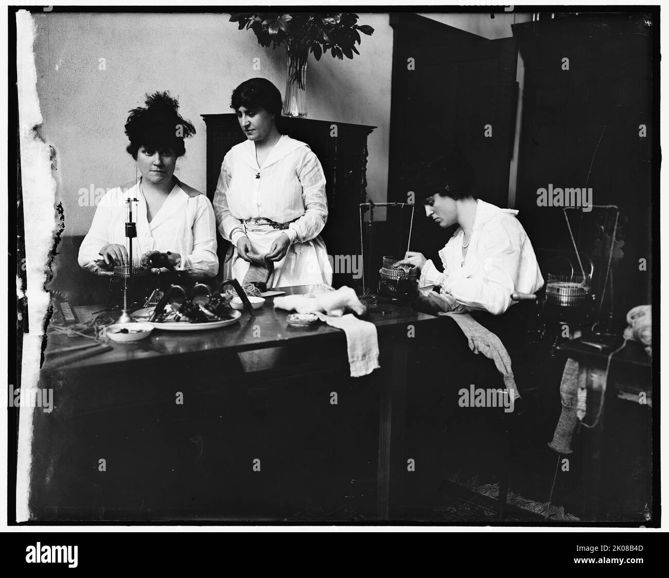 Sig.ra Josephine Patton; sig.ra C.C. Marsh; sig.ra George D. Widener, tra il 1910 e il 1920. Donna che usa macchine per maglieria per lavorare i calzini. Foto Stock