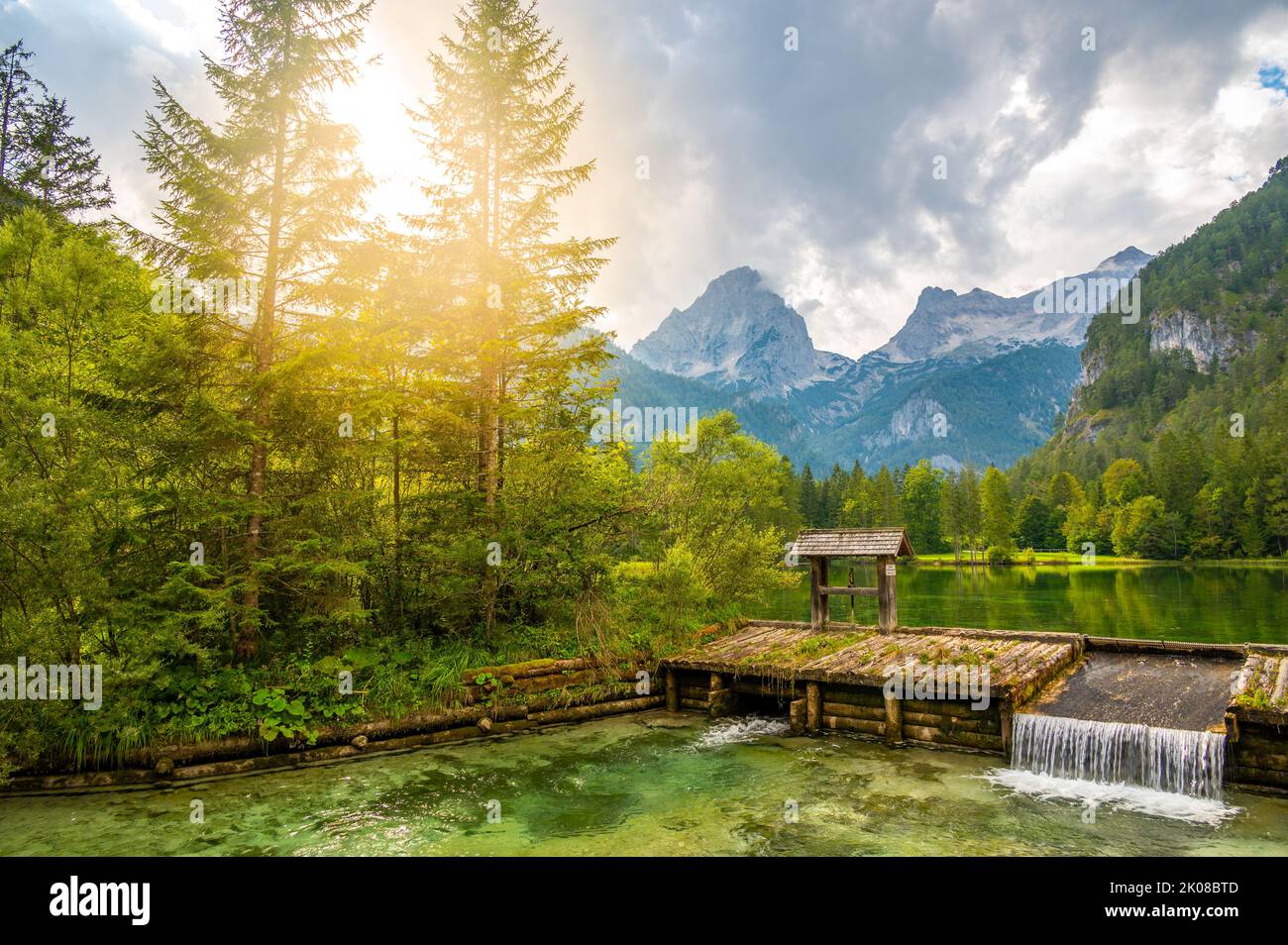 Famoso lago verde Schiederweiher vicino al villaggio di Hinterstoder. Piccolo stramazzo e diga sul lago con acqua corrente. Grandi montagne austriache sullo sfondo. Morbido Foto Stock