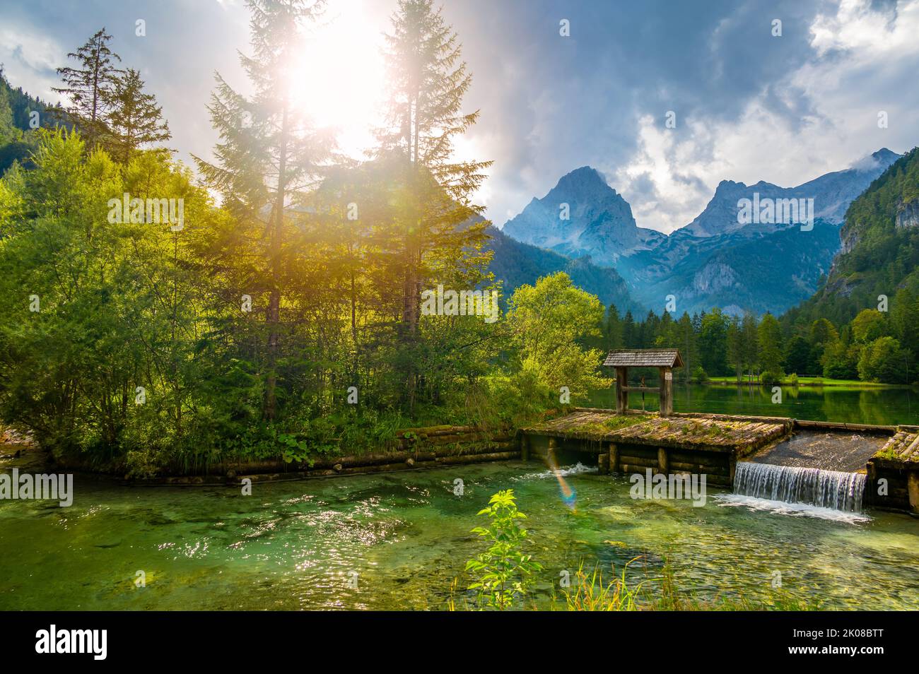 Famoso lago verde Schiederweiher vicino al villaggio di Hinterstoder. Piccolo stramazzo e diga sul lago con acqua corrente. Grandi montagne austriache sullo sfondo. Morbido Foto Stock