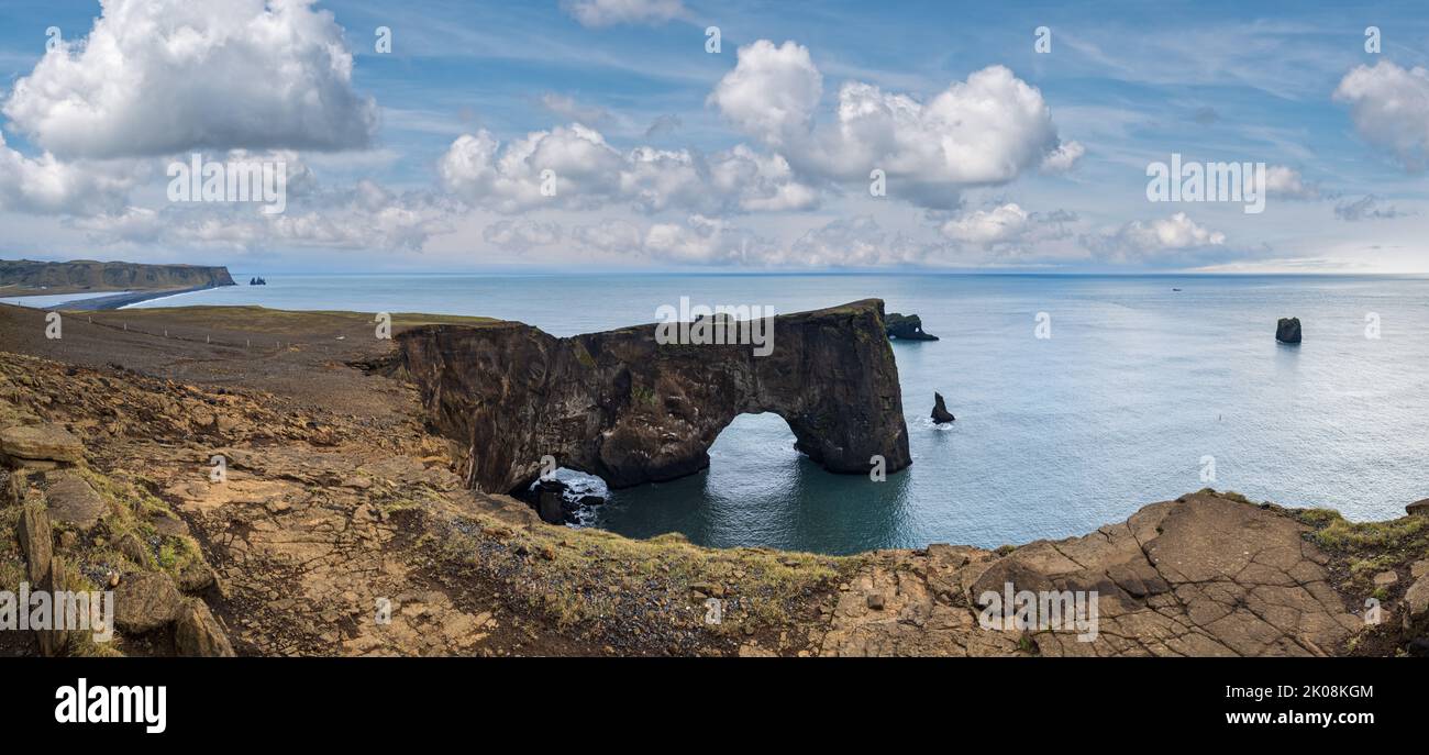 Pittoresca vista serale autunnale sulle scogliere della costa di Dyrholaey e sull'arco roccioso, Vik, Islanda del Sud. Reynisfjara oceano nero sabbia vulcanica spiaggia in lontano. Foto Stock