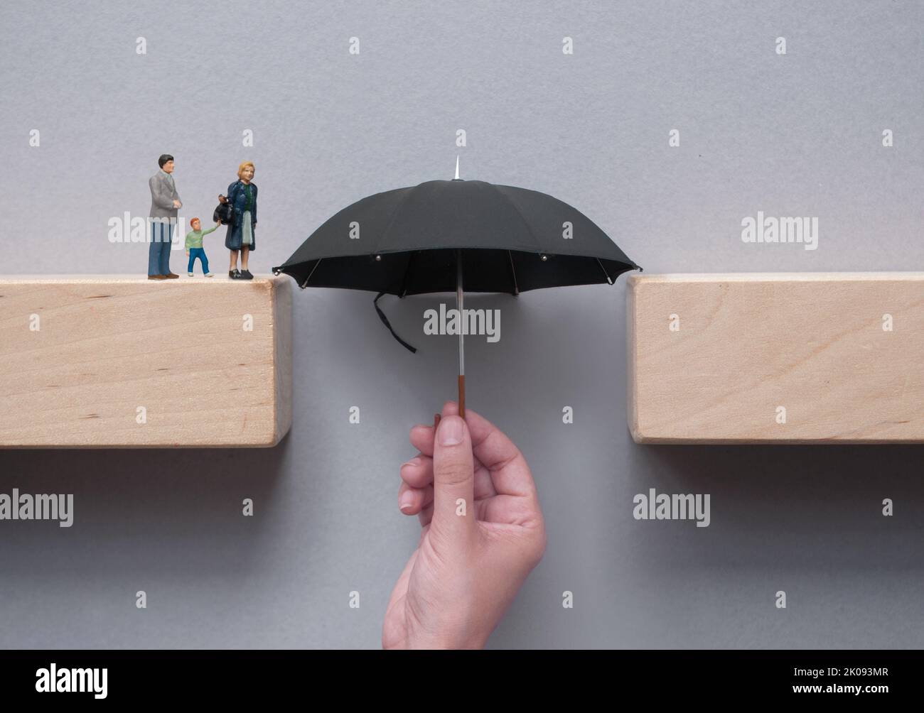 Ombrello con mano che colma lo spazio tra blocchi di legno attraversamento sicuro Foto Stock