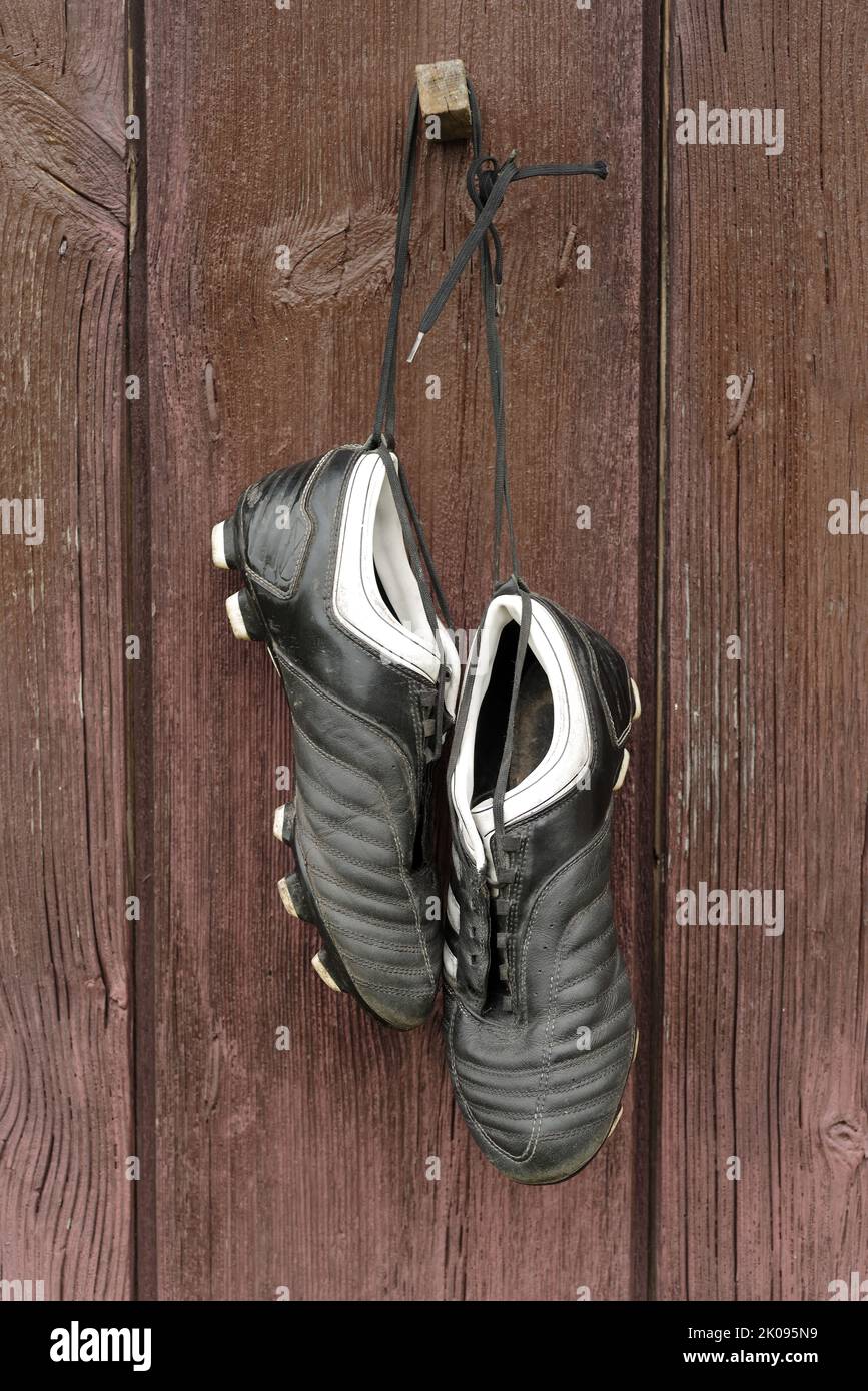 Un paio di stivali da calcio appesi su un muro di legno. La fine della carriera calcistica Foto Stock