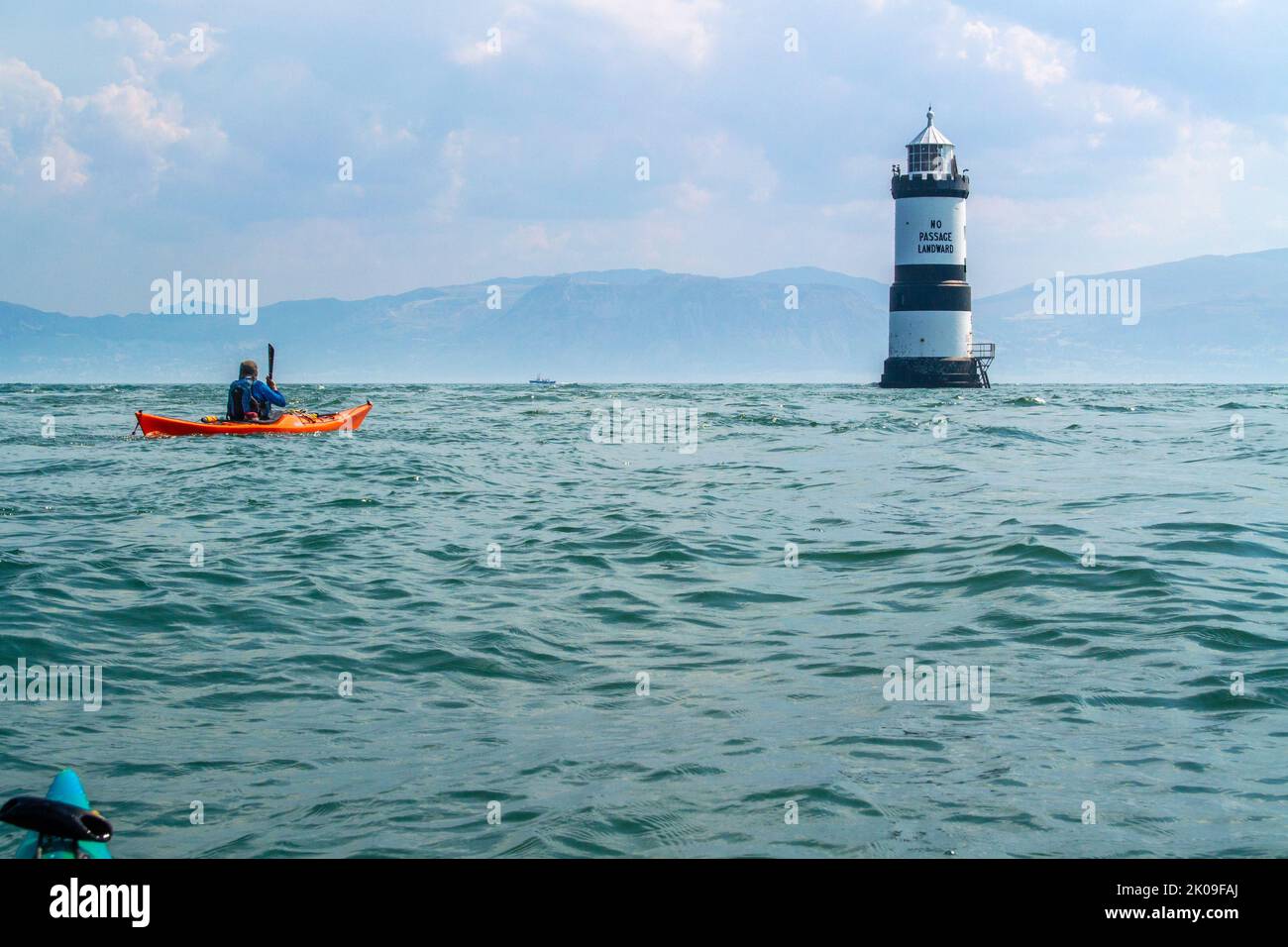 Kayak da mare vicino al Trwyn Du Lighthouse, noto anche come Penmon Lighthouse, al largo di Puffin Island, sulla costa di Anglesey, Galles, Regno Unito Foto Stock