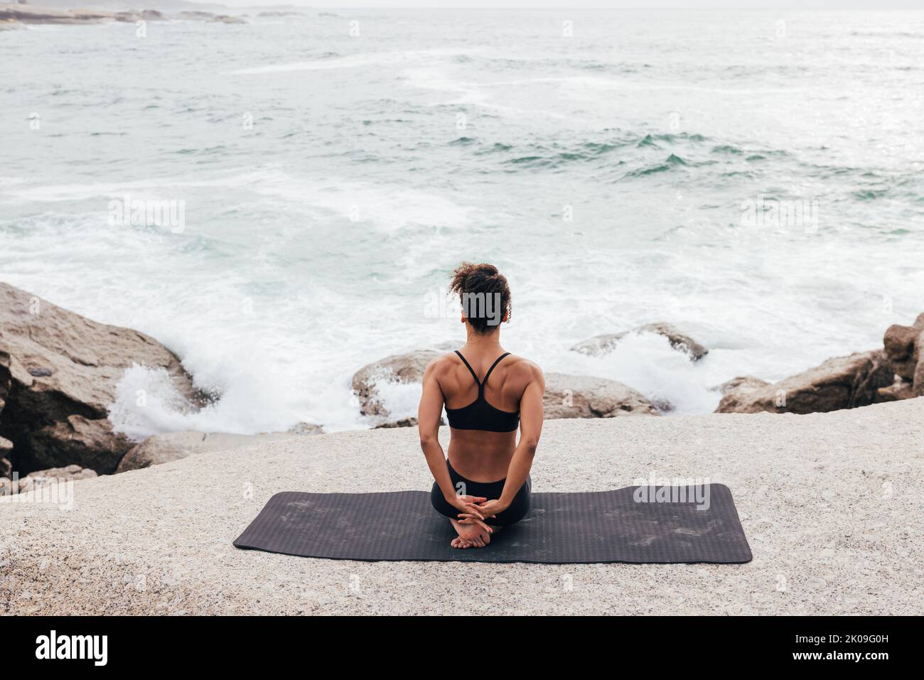 Donna seduta sul tappeto da oceano riscaldamento mani Foto Stock