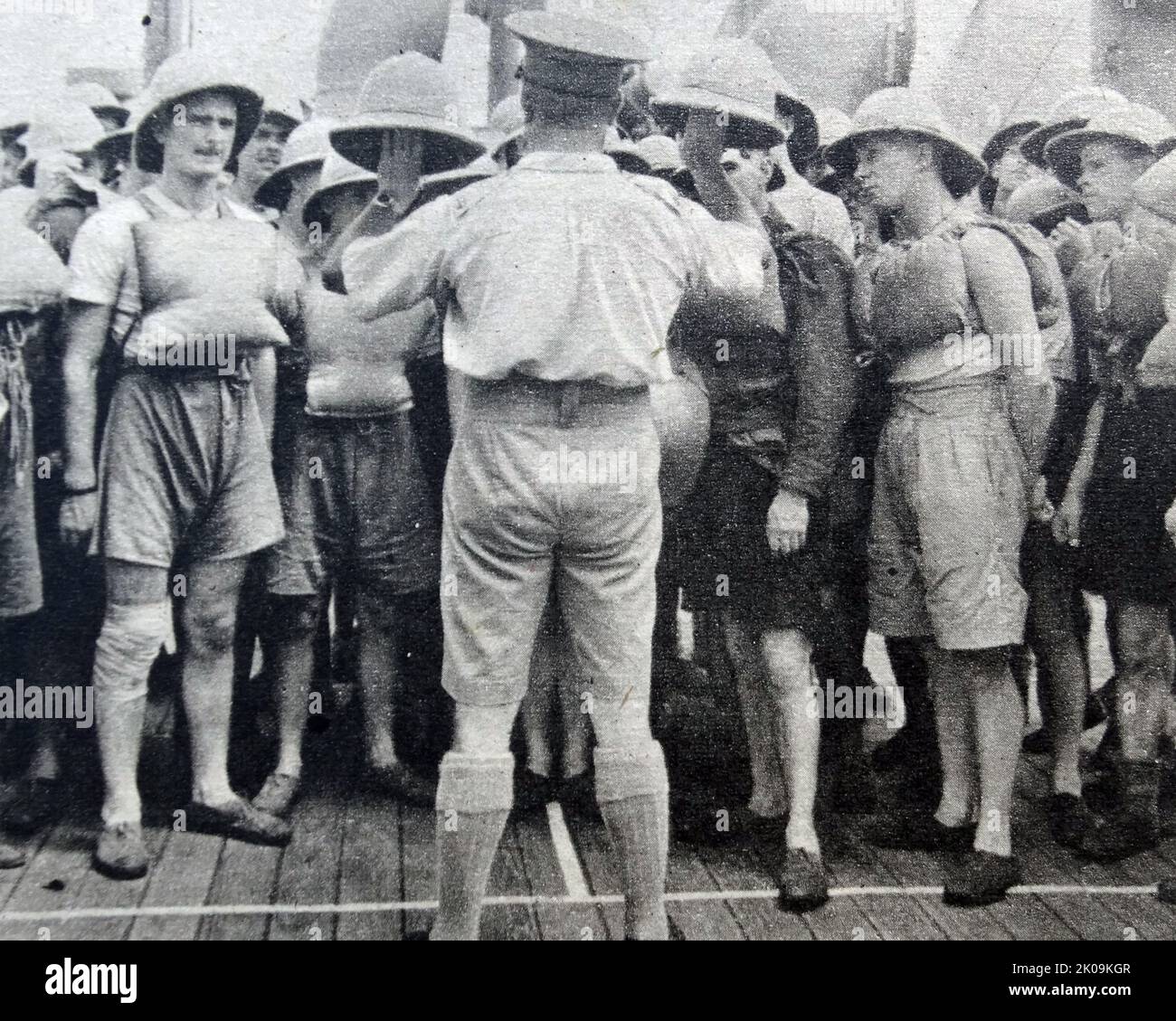 Le truppe dell'esercito britannico si abituano a indossare topee come parte del loro kit su una troopship durante la seconda guerra mondiale Foto Stock