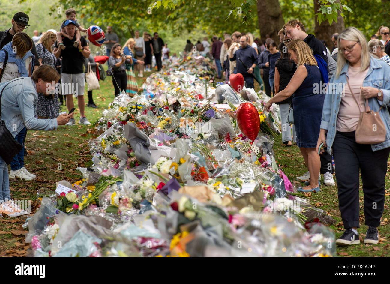 I membri del pubblico si riuniscono per deporre fiori nel parco verde vicino a Buckingham Palace oggi dopo la morte di sua Maestà la Regina Elisabetta II Foto Stock