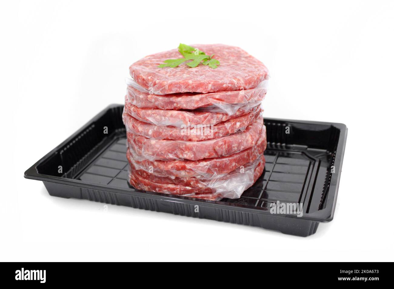 Pila di polpette fresche di hamburger di carne cruda in vassoio nero isolato su sfondo bianco Foto Stock