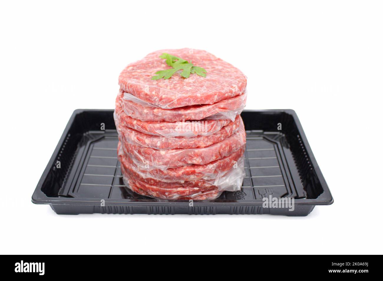 Pila di polpette fresche di hamburger di carne cruda in vassoio nero isolato su sfondo bianco Foto Stock