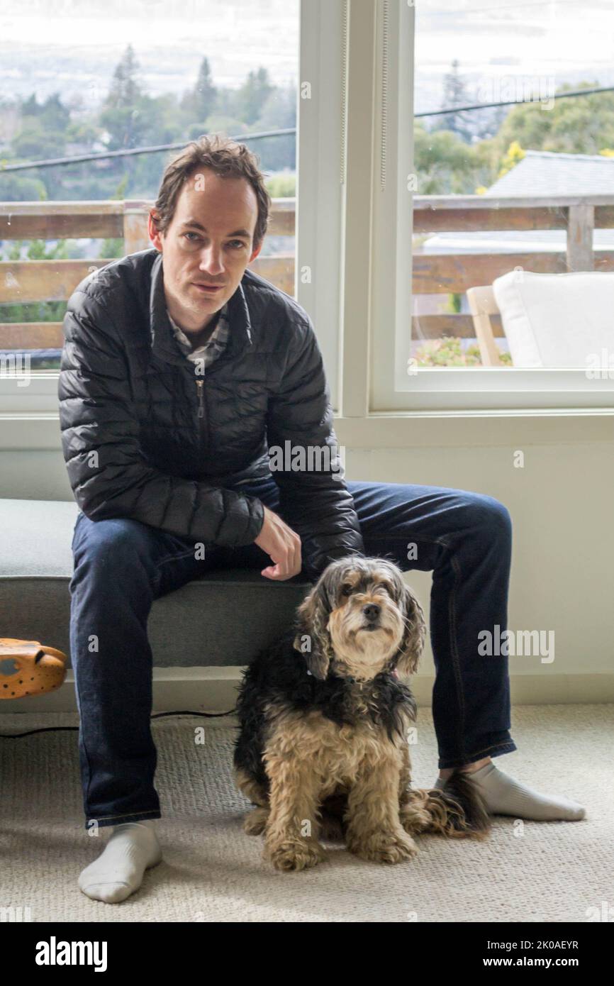 Uomo seduto con un cane Foto Stock