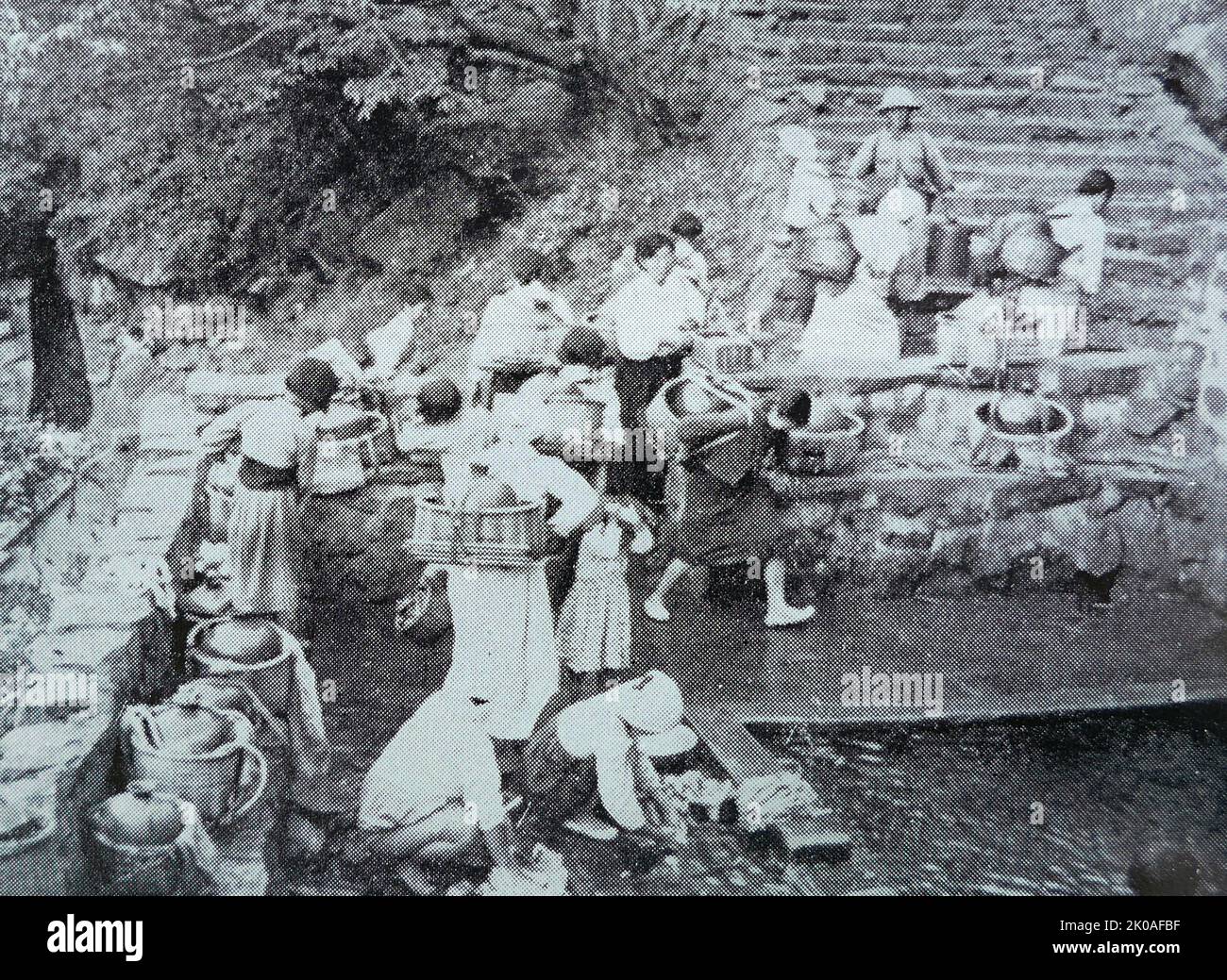 Una scena di villaggio nell'isola di Jeju. Le donne vengono al pozzo comune del villaggio per la fornitura di acqua Foto Stock