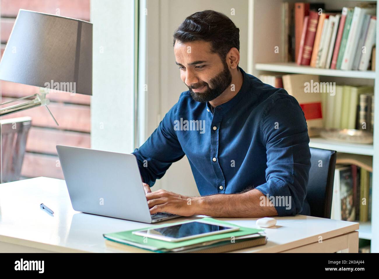 Uomo d'affari indiano a distanza che lavora su un computer portatile seduto in ufficio a casa. Foto Stock