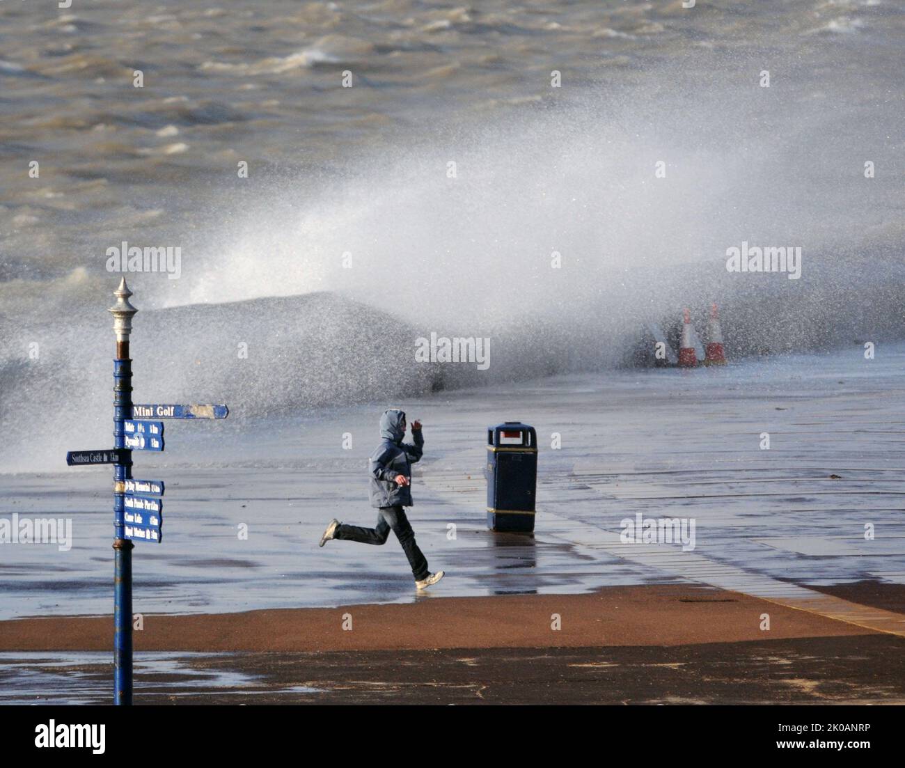 CORRENDO PER LA COPERTURA COME ONDE GIGANTI SFERRANO IL LUNGOMARE A SOUTHSEA, HANTS. PIC MIKE WALKER, 2014 FOTO DI MIKE WALKER Foto Stock