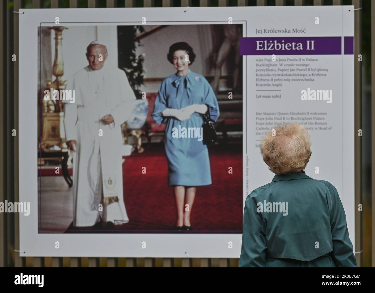 VARSAVIA, POLONIA. 10 settembre 2022. Una donna sta camminando davanti ad una mostra commemorativa della visita della Regina in Polonia nel 1996 vista su una recinzione dell'Ambasciata Britannica a Varsavia. . La regina Elisabetta II morì al castello di Balmoral in Scozia il 8 settembre 2022, ed è succeduta dal suo figlio maggiore, re Carlo III Credit: ASWphoto/Alamy Live News Foto Stock