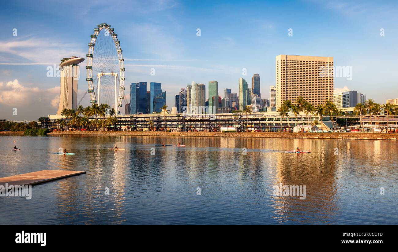 Panorama dello skyline della città di Singapore presso il moderno edificio business del centro all'alba con nuvole e luce solare e architettura riflessa sull'acqua Foto Stock