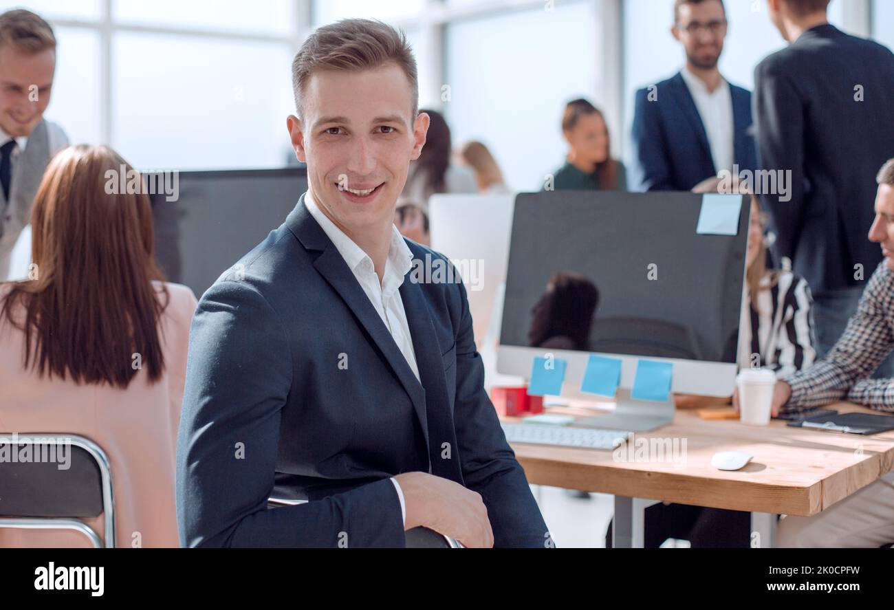 Giovane uomo d'affari seduto alla sua scrivania e guardando la macchina fotografica Foto Stock