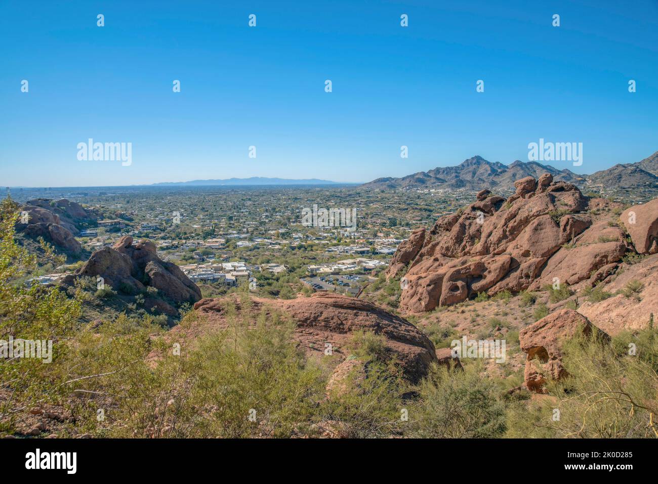 Vista dell'area residenziale sottostante dalla scogliera sul Monte Camelback a Phoenix, Arizona. Ci sono erbe e grandi rocce sulla scogliera vicino al hikin Foto Stock