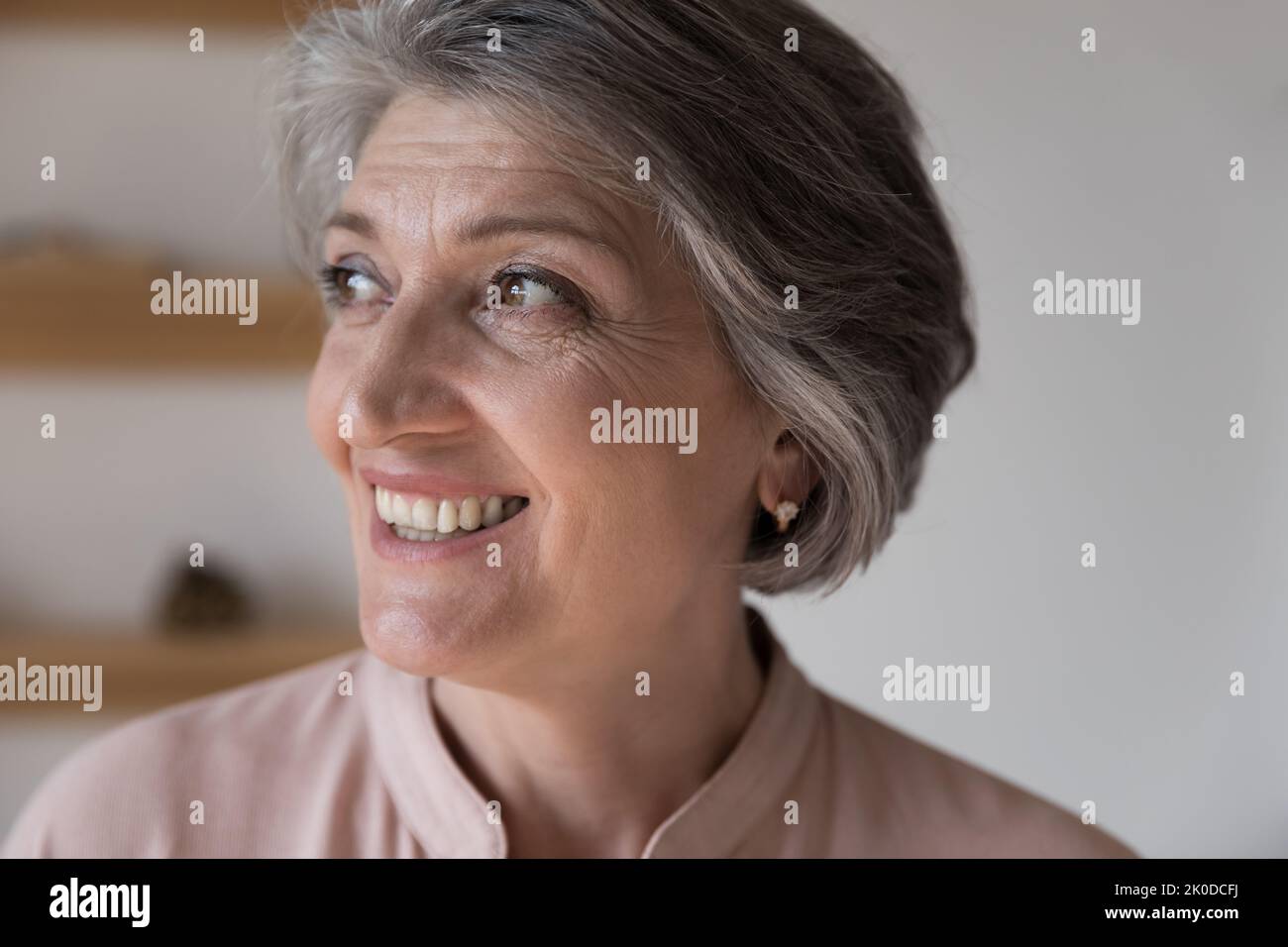 Felice donna pensionato di sogno grigio capelli guardando via Foto Stock