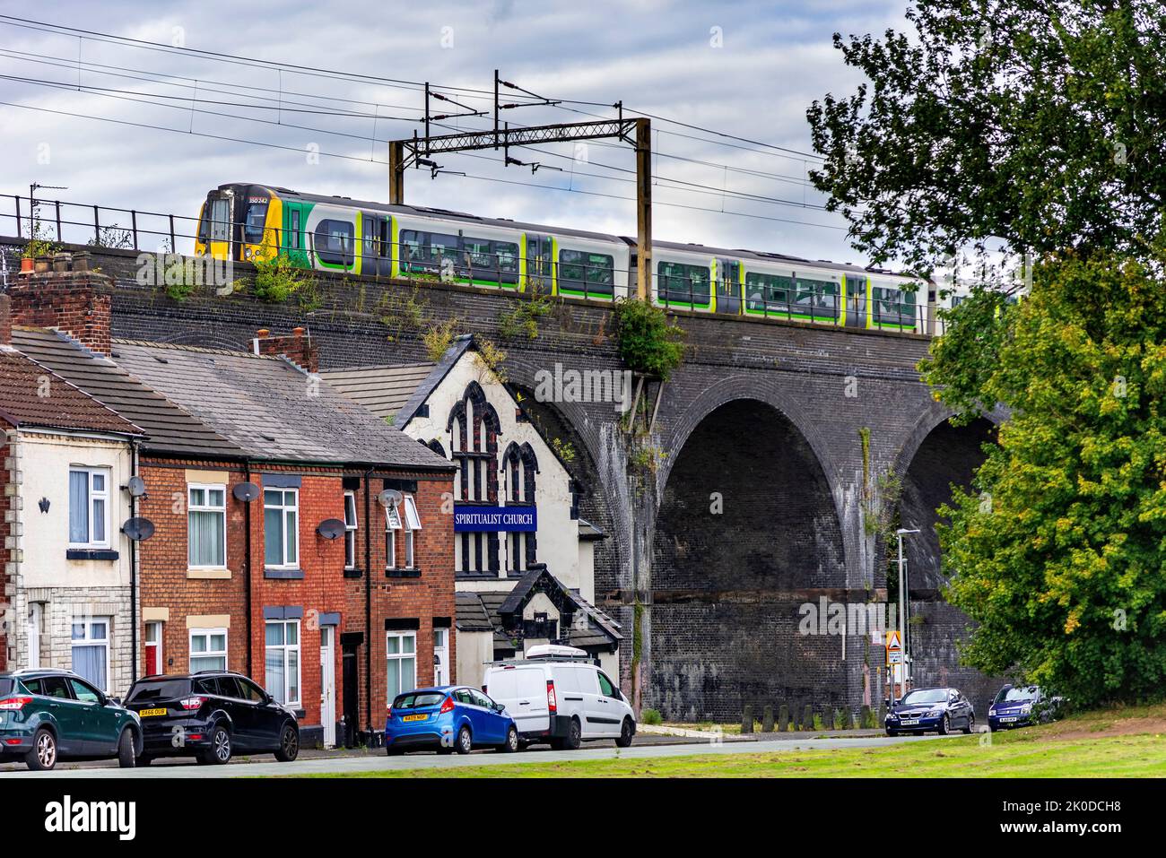 Ferrovia di Londra e Nord-Ovest. La classe 350 del treno elettrico a più unità si dirige verso Liverpool passando sopra le case sotto gli archi del ponte. Foto Stock