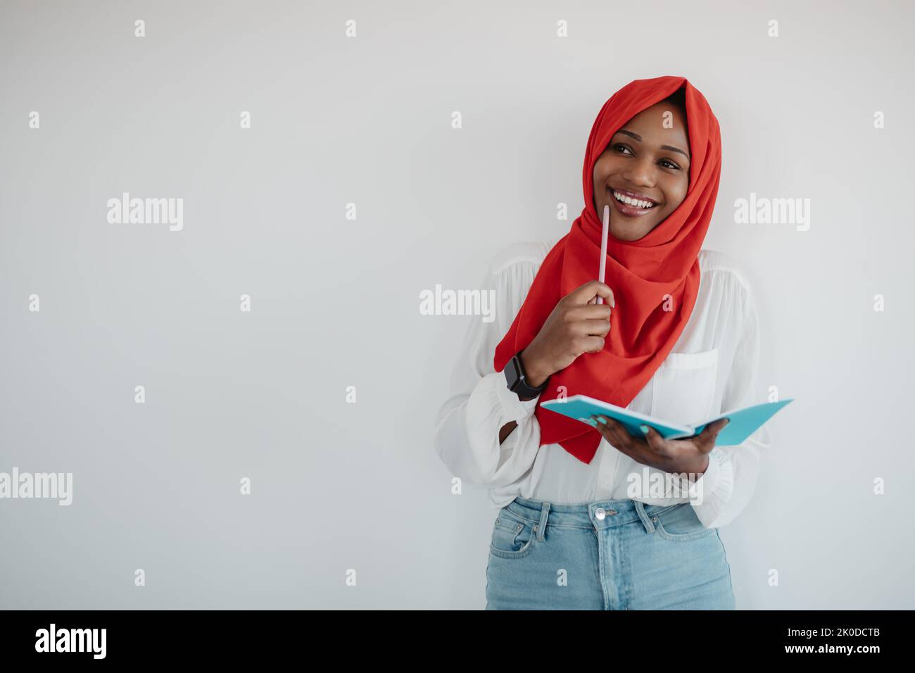 Ricerca di idee. Donna afro-americana premurosa in hijab tenendo il blocco note e la matita, sfondo chiaro, spazio di copia Foto Stock