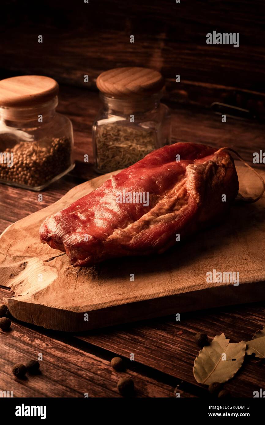 Carne su un tavolo di legno con aggiunta di erbe fresche e spezie aromatiche. Prodotto naturale di fattoria biologica, prodotto con metodi tradizionali Foto Stock