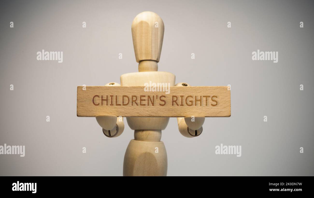 Uomo di legno che tiene in mano scritto diritti dei bambini segno su di esso. Questioni sociali. Foto Stock
