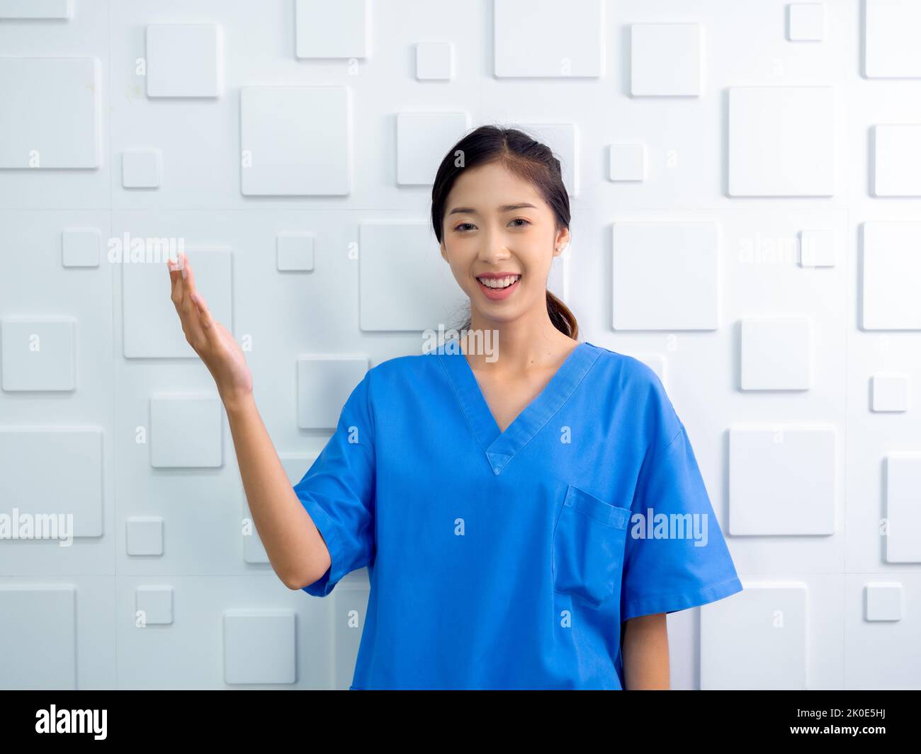 Ritratto di amichevole, allegro, sorriso fiducioso medico asiatico donna o infermiera facendo gesto esplicativo con la mano su sfondo bianco, guardando ca Foto Stock