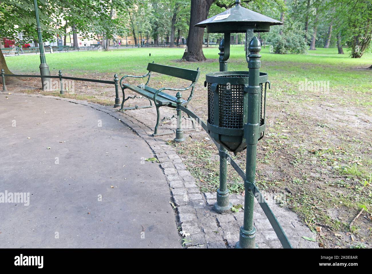 Una panca di metallo e un cestino possono in un parco nella città polacca di Cracovia. Foto Stock