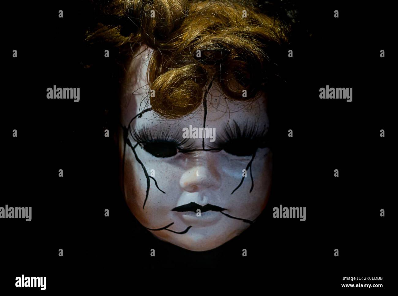 bambola in porcellana stile horror con capelli biondi faccia al buio Foto Stock