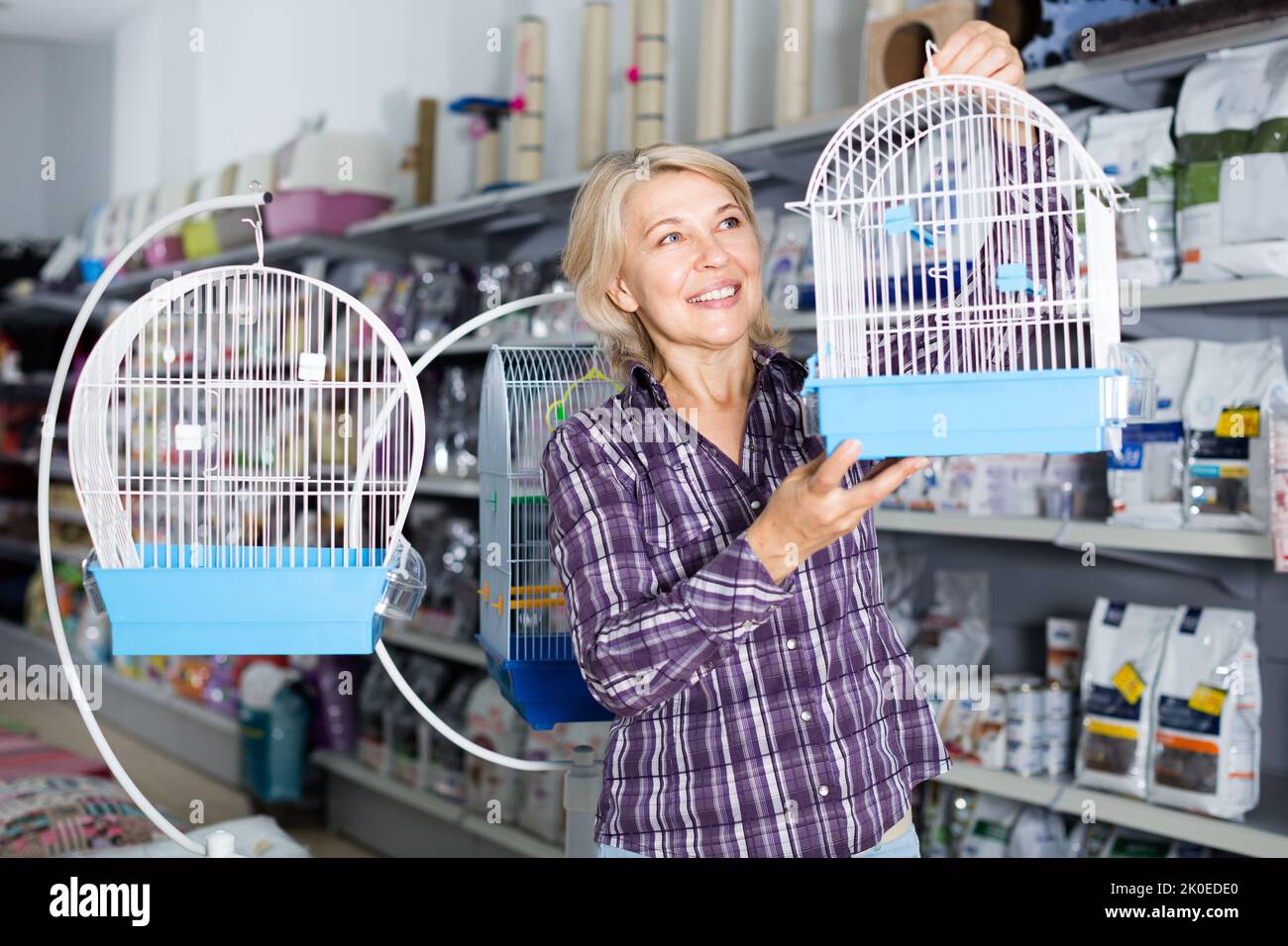 donna che acquista gabbia per uccello in negozio Foto Stock