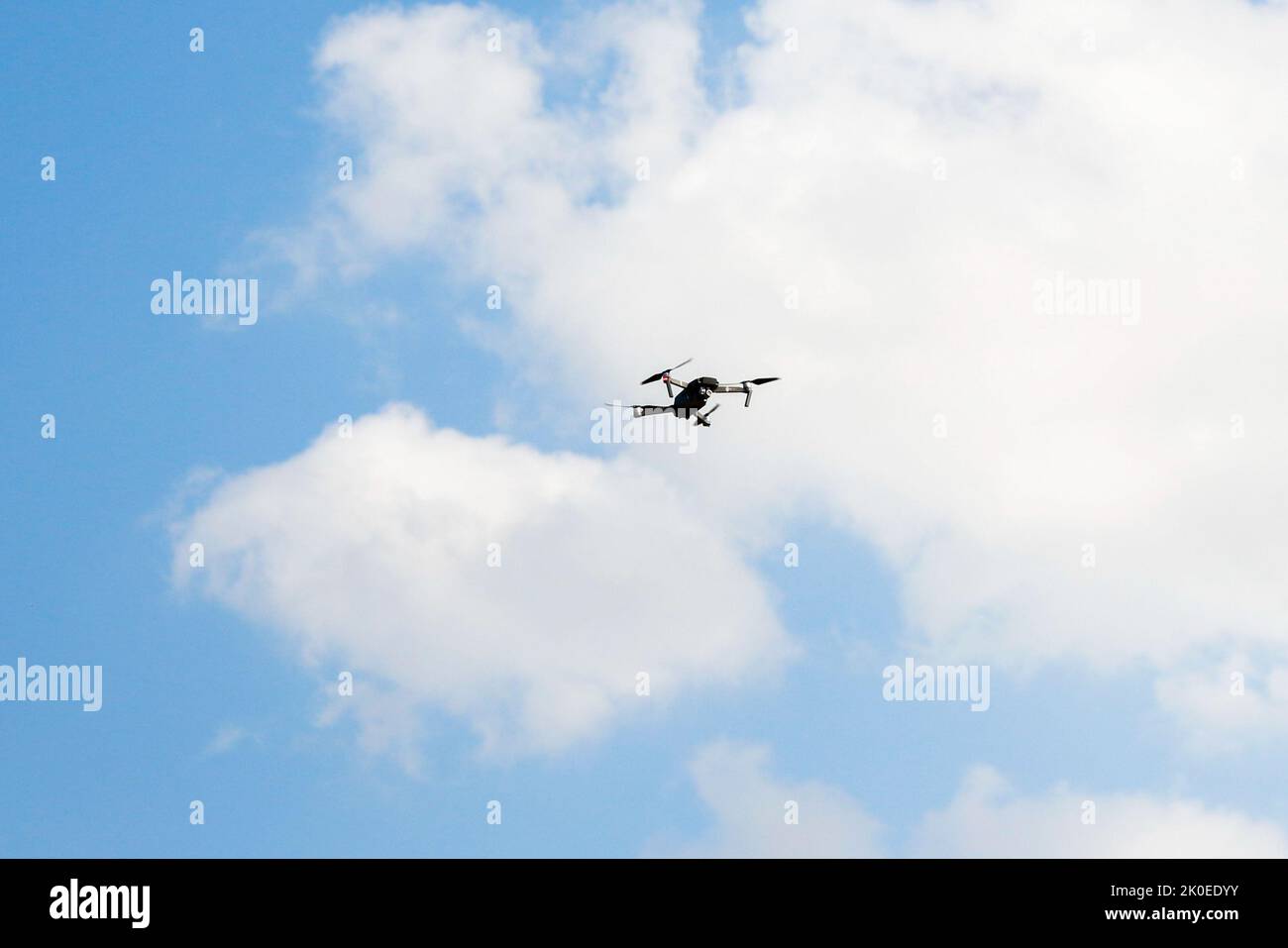 Defocalizzare il drone di guerra. Drone che vola in un cielo blu. Il veicolo aereo senza equipaggio dell'esercito nero con quattro eliche e pale si trova sullo sfondo blu del cielo. W Foto Stock