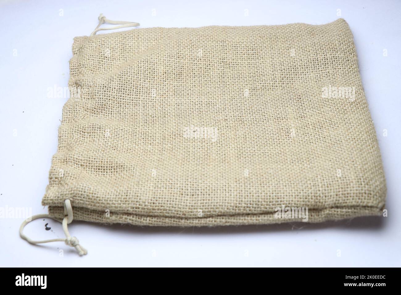 Una piccola borsa in iuta realizzata in fibre naturali e completamente rispettosa dell'ambiente, utilizzata per l'imballaggio di regali tenuti su sfondo bianco Foto Stock