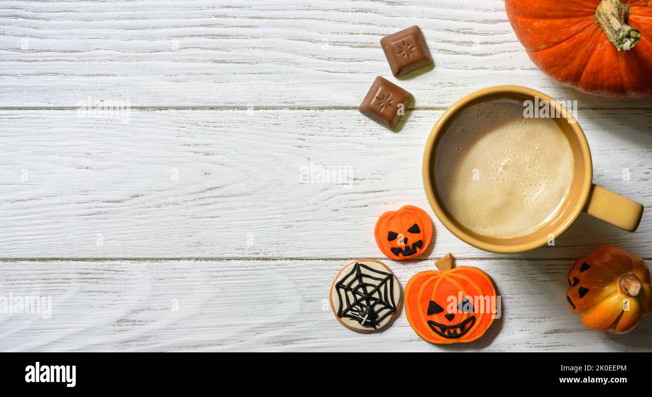 Tema Halloween e caffè, zucca arancione, dolci e tazza su tavolo bianco, vista dall'alto. Cibo vacanza su tavole di legno sfondo con spazio, piatto. Parte Foto Stock