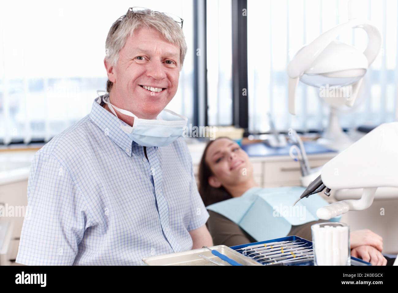 Dentista felice con paziente. Ritratto di dentista maturo sorridente con paziente femminile sullo sfondo. Foto Stock