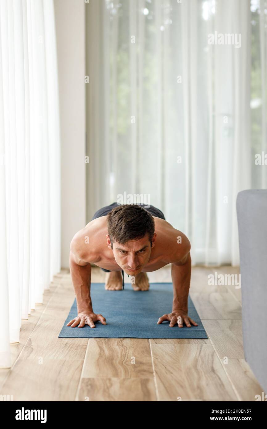 Uomo di mezza età che esegue il chaturanga yoga posa durante la sua routine fisica mattutina Foto Stock