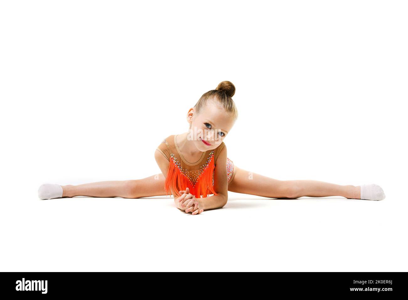 Flessibile piccola ginnastica scuola elementare ragazza seduta in fronte split, sport professionale per i bambini, grazioso bambino su sfondo isolato Foto Stock