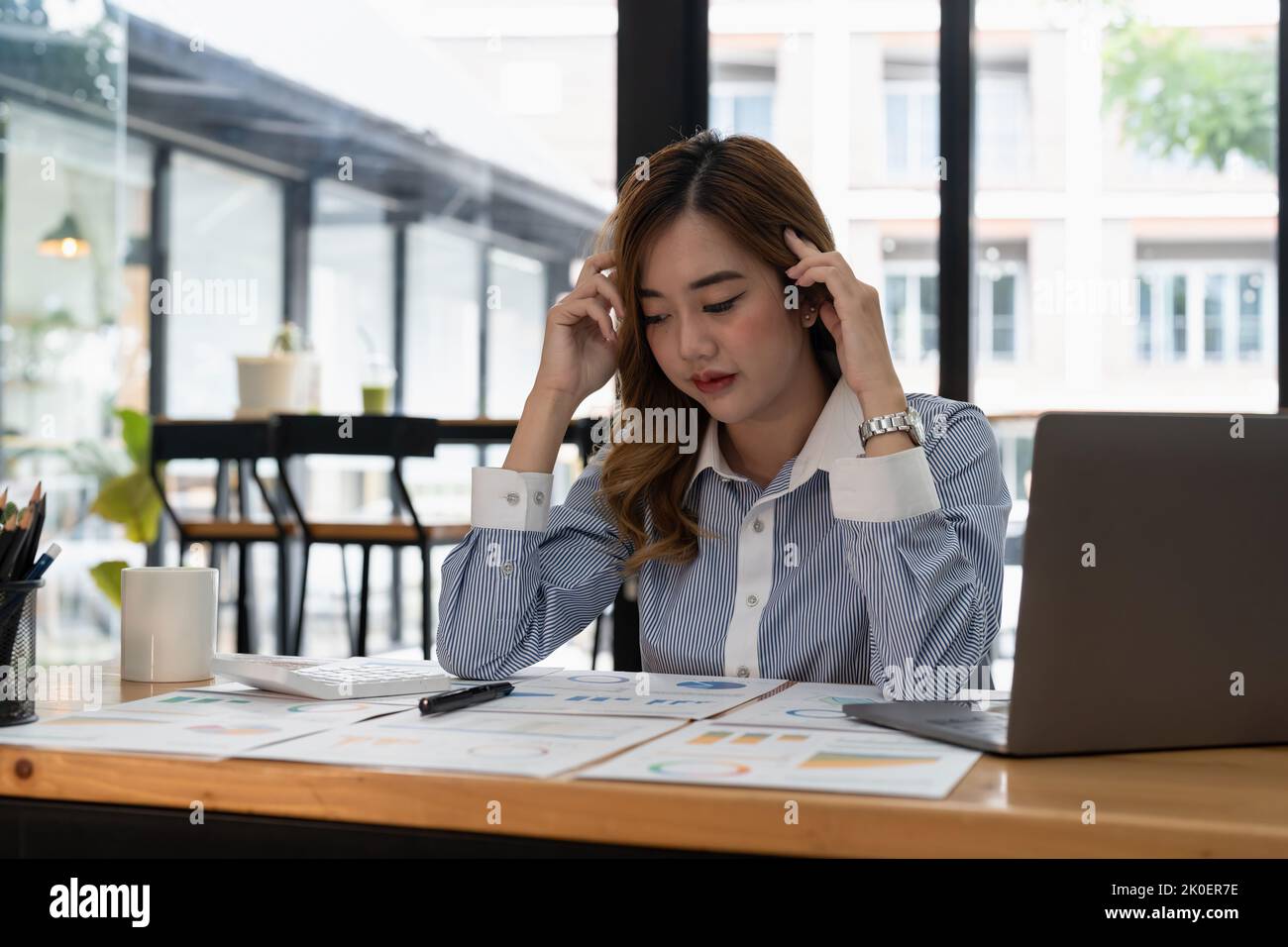 Donna asiatica d'affari ottenere stressato e mal di testa mentre avendo un problema al lavoro in ufficio Foto Stock