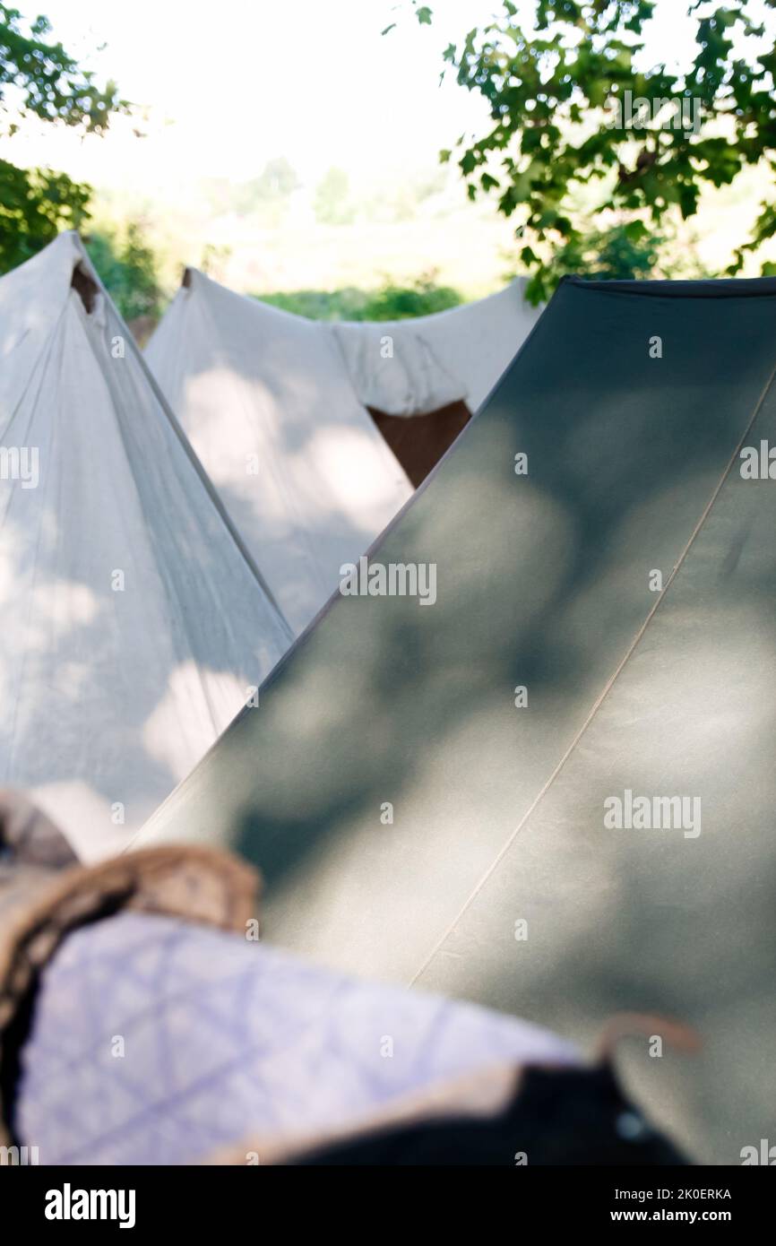 Defocalizzare le tende verdi sul festival di storia. Campeggio militare in una zona di riposo. Una tenda città di molte tende. Su un prato verde nel bosco. Un sacco di campeggio Foto Stock