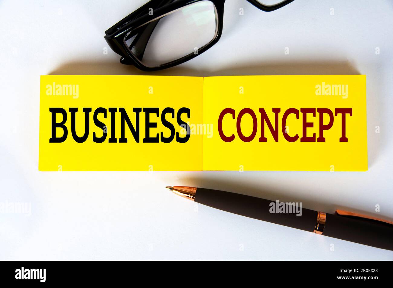 Testo aziendale su blocco note giallo con vetro e penna su sfondo bianco. Concetto aziendale. Foto Stock