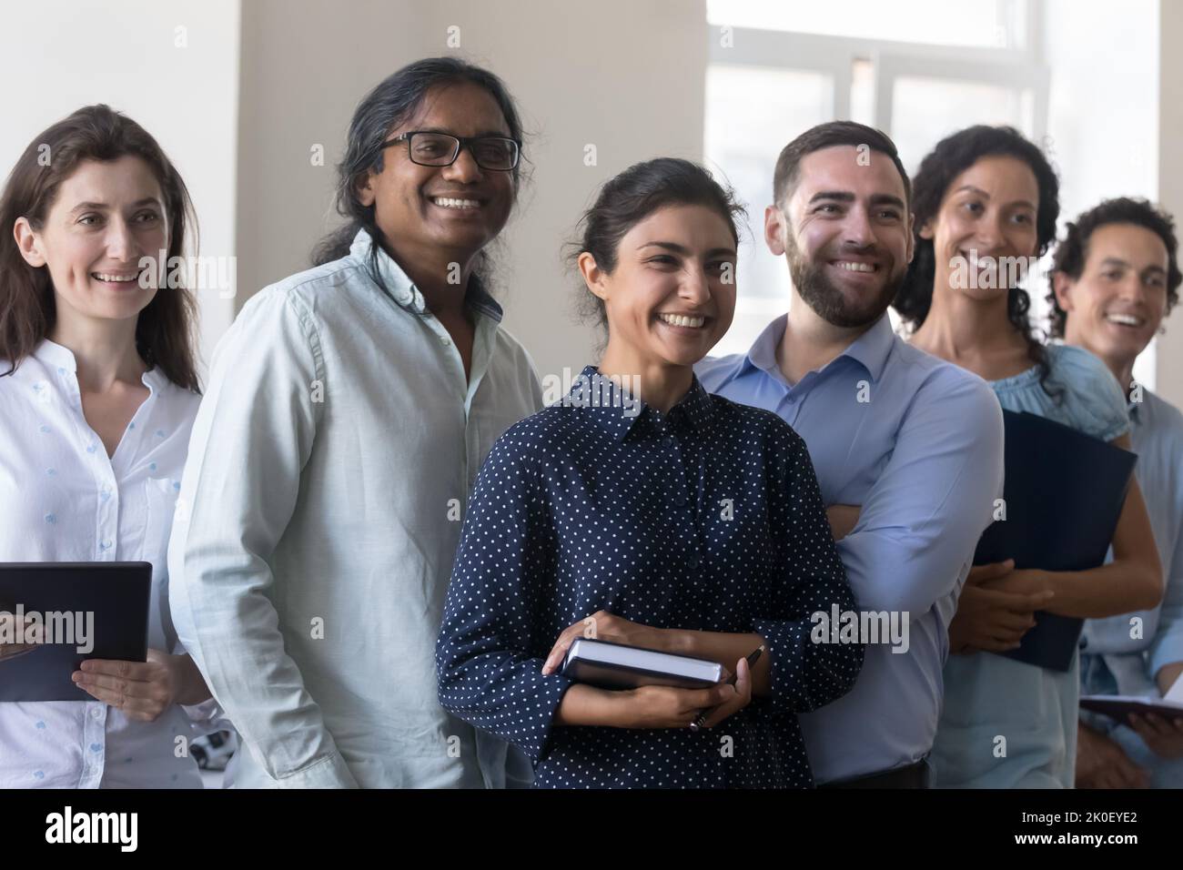 Felice allegro team di progetto multietnico in piedi insieme in ufficio Foto Stock