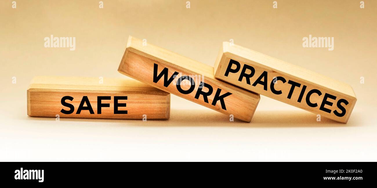 Blocchi di legno con le parole pratiche di lavoro sicure su uno sfondo chiaro Foto Stock