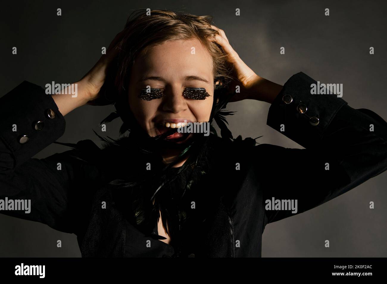 Ragazza bionda che si aggrappa la testa indossando spotty false ciglia e piume colletto ridere Foto Stock