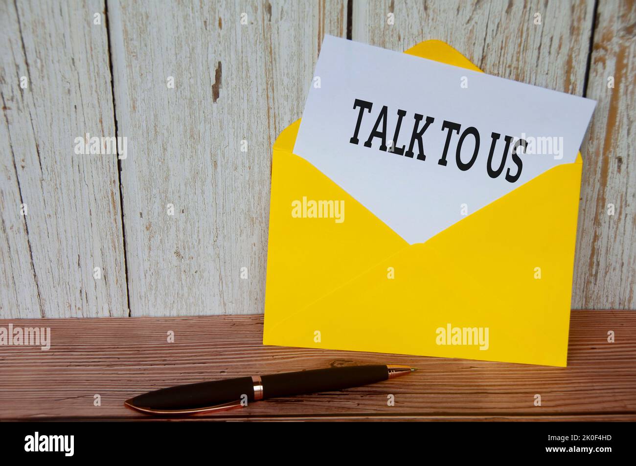 Parla con noi testo su blocco note bianco in busta gialla. Concetto di servizio clienti. Foto Stock