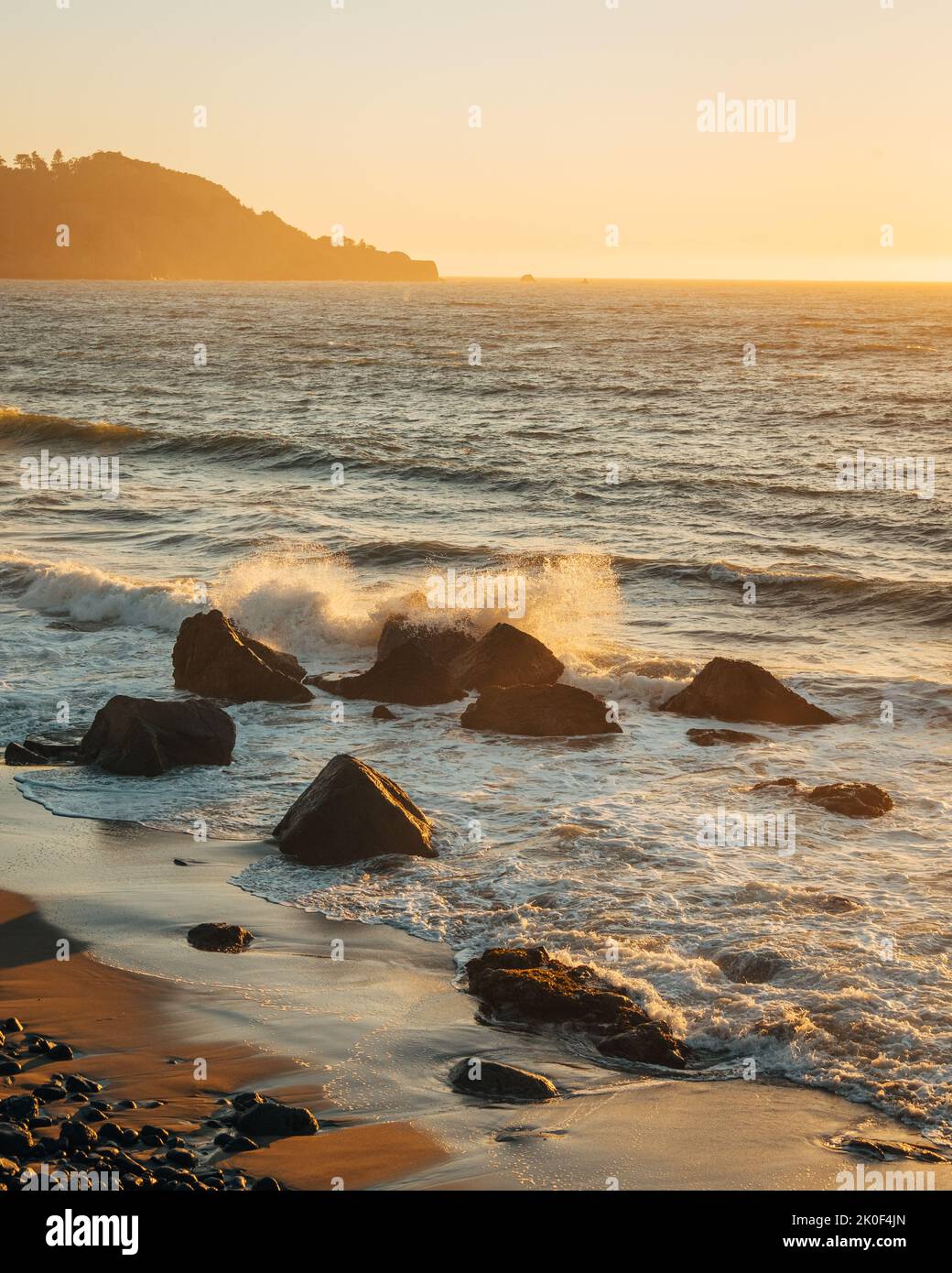 Onde che si schiantano sulle rocce al tramonto, a Marshalls Beach , San Francisco, California Foto Stock