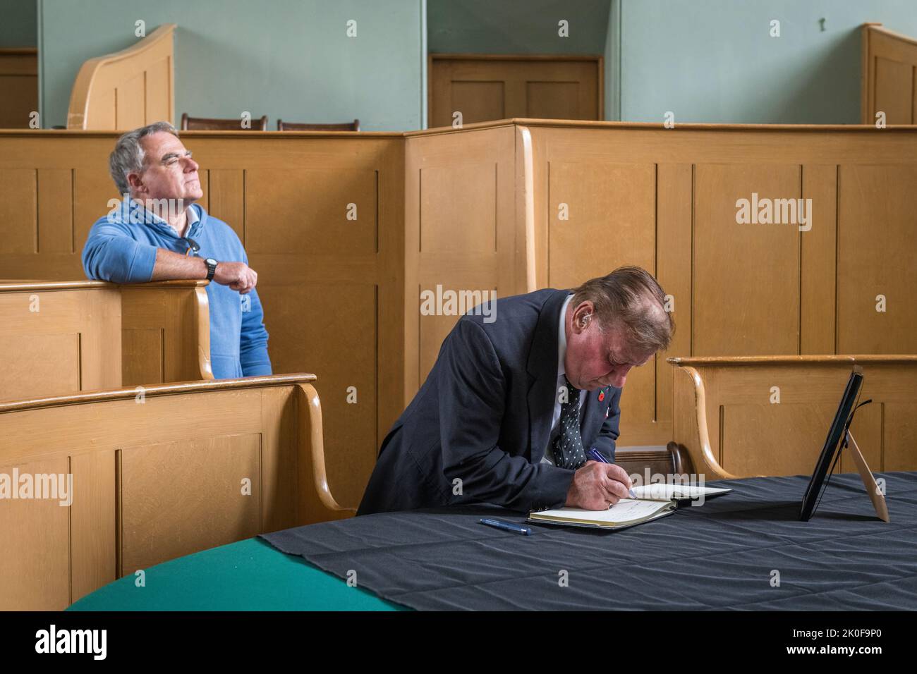 Nella piccola città di confine gallese di Presteigne, la vecchia città della contea di Radnorshire, l'agricoltore Brian Lloyd firma un libro di condoglianze per la defunto Regina Elisabetta II Il libro è conservato nella vecchia corte del Giudice's Lodging, nel centro della città. Foto Stock