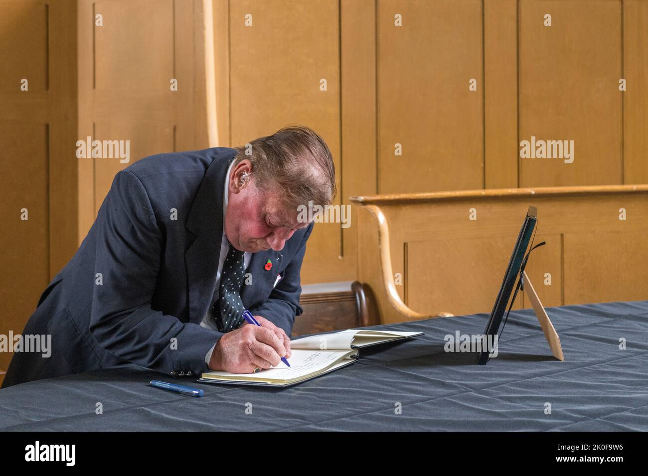 Nella piccola città di confine gallese di Presteigne, la vecchia città della contea di Radnorshire, il contadino locale Brian Lloyd firma un libro di condoglianze per la defunto Regina Elisabetta II Il libro è conservato nella vecchia corte del Giudice's Lodging, nel centro della città. Foto Stock