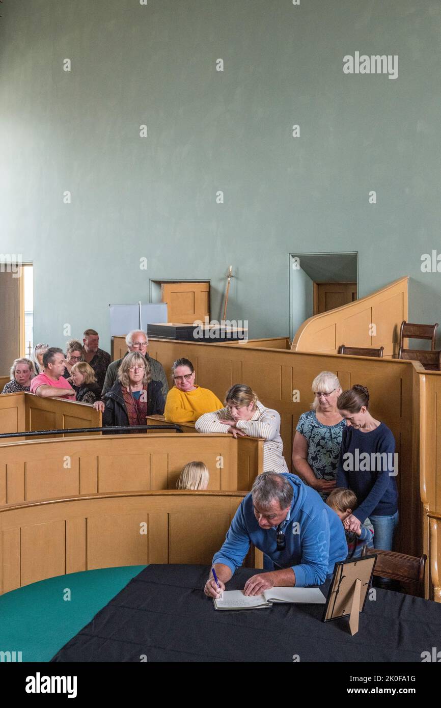 Nella piccola città di confine gallese di Presteigne, la vecchia città della contea di Radnorshire, il locale Ken Rodmell (in testa alla coda) firma un libro di condoglianze per la defunto Regina Elisabetta II Il libro è conservato nella vecchia corte del Giudice's Lodging, nel centro della città. Foto Stock