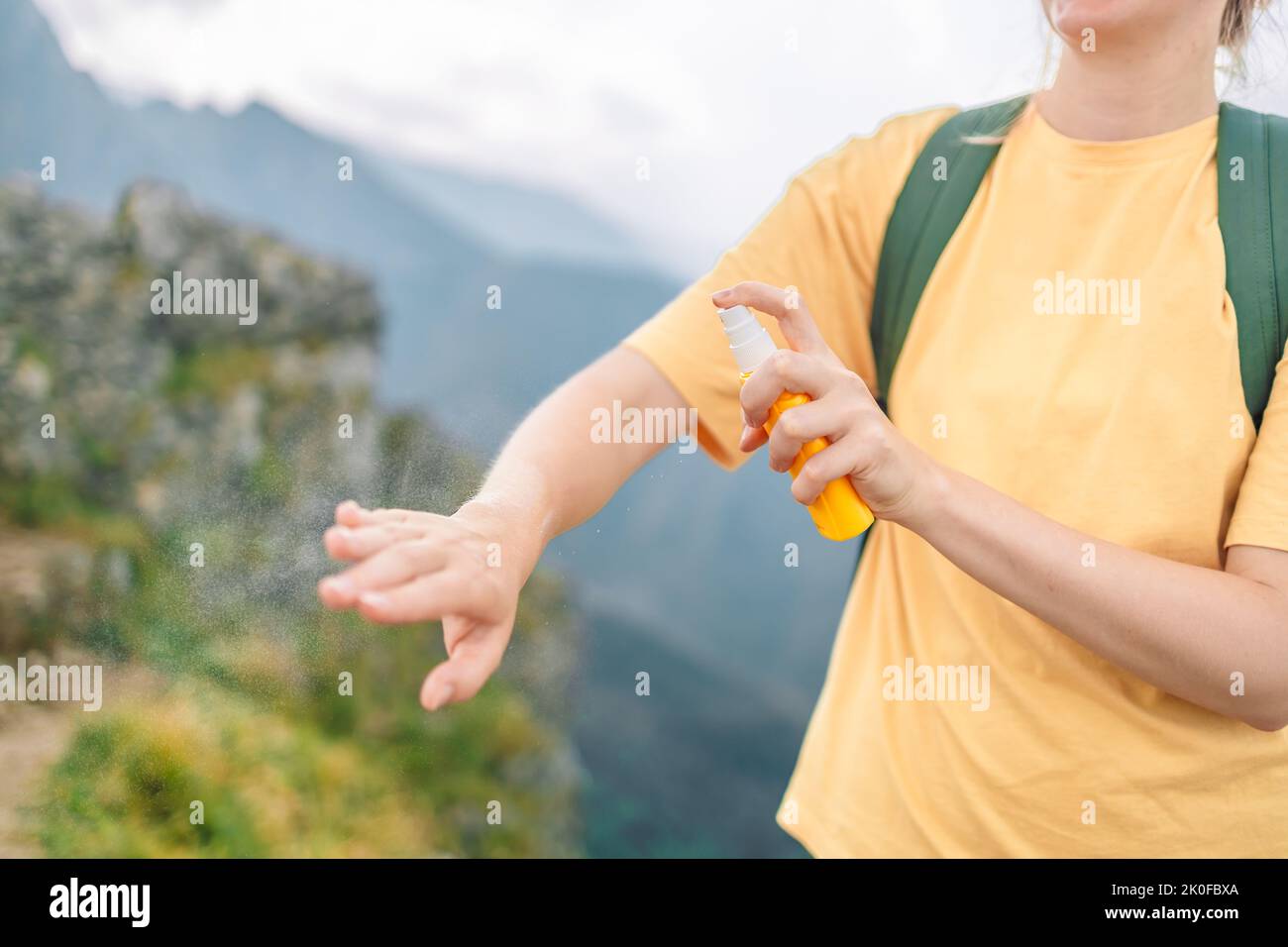 Donna che applica repellente insetto contro zanzara e zecca sulla sua mano durante l'escursione in montagna natura. Protezione della pelle contro il morso di insetto Foto Stock