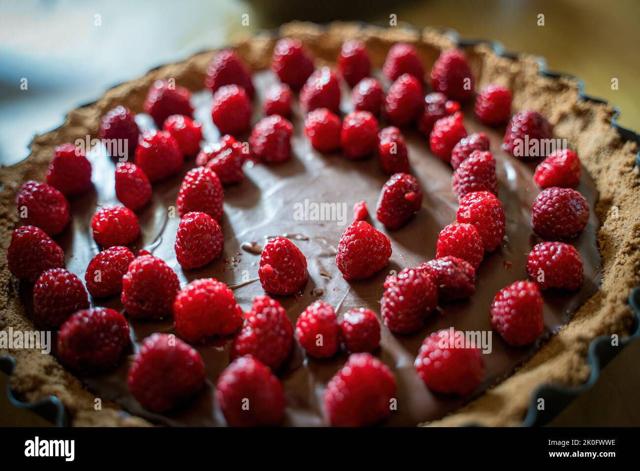 Deliziosa crostata di cioccolato con diversi lamponi in cima, primo piano di torta di frutta dessert, focus selettivo Foto Stock