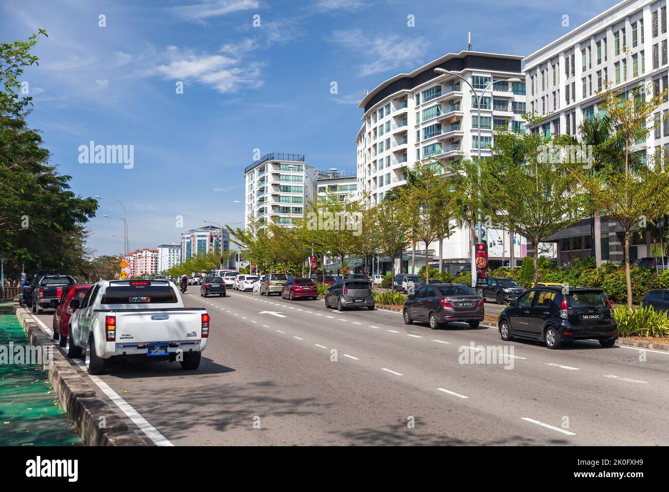 Kota Kinabalu, Malesia - 17 marzo 2019: Kota Kinabalu in una giornata di sole. Vista sulla strada con edifici moderni e auto parcheggiate Foto Stock